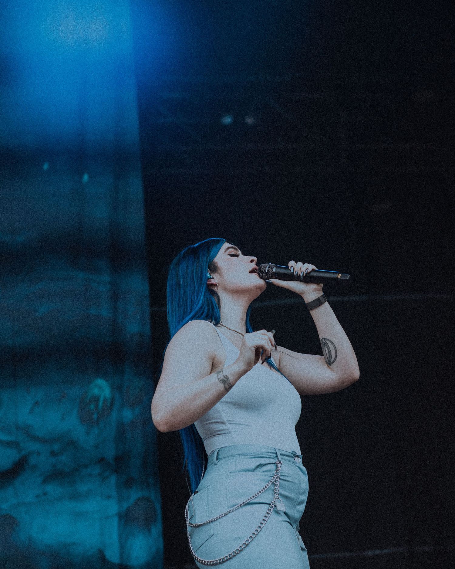 Singer performs on stage bathed in moody blue lighting effects.