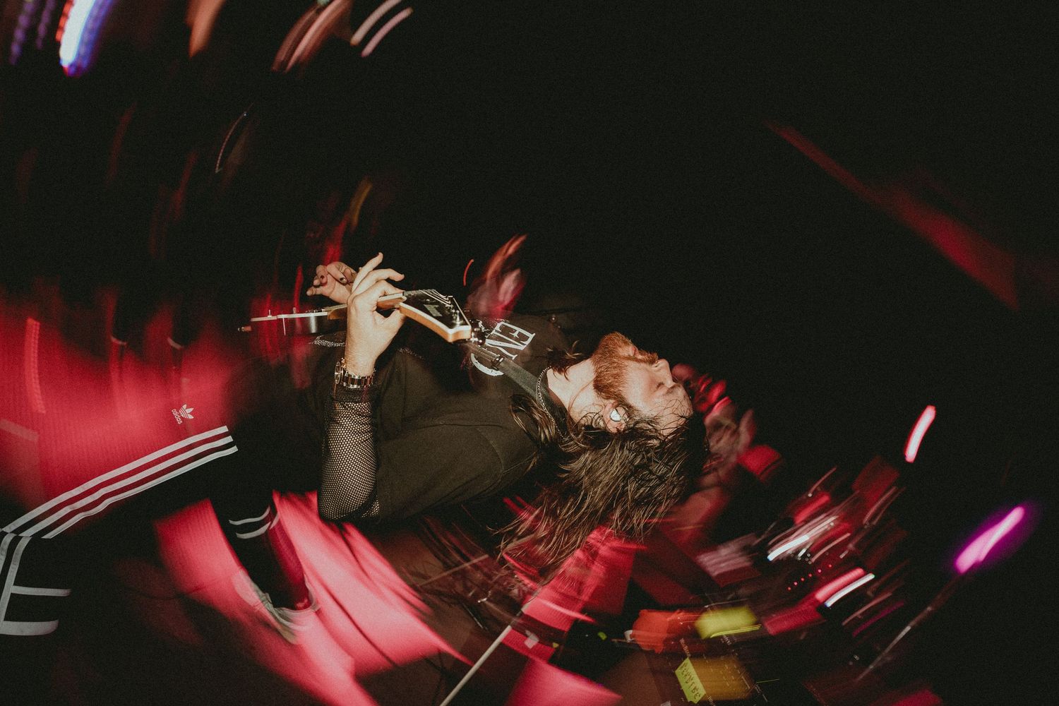 Dynamic concert performance with dramatic red lighting and silhouetted musicians on stage.