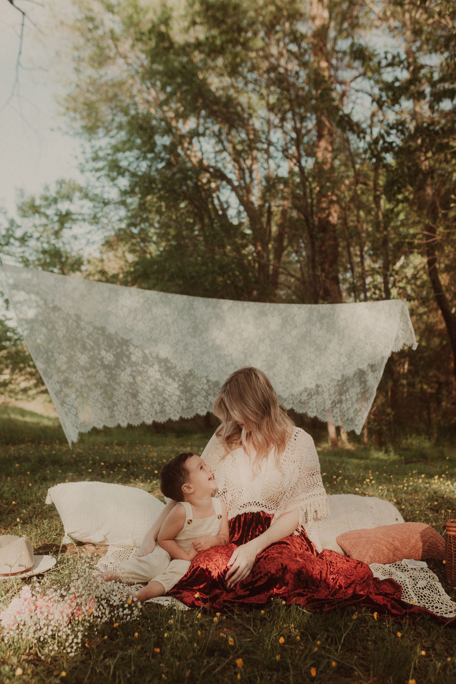 Two people relax on white blanket among wildflowers at golden hour.