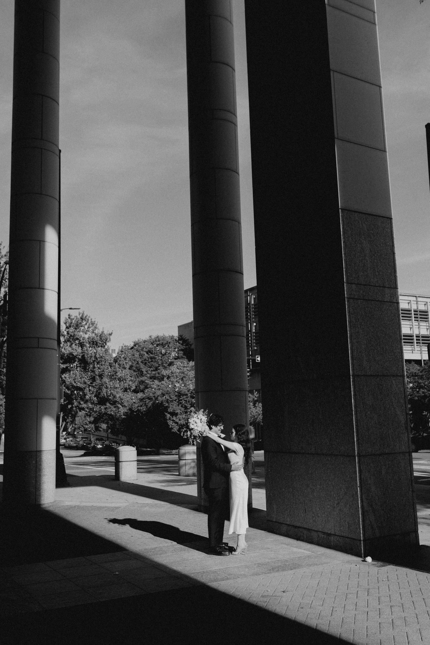 Dramatic black and white photo of architectural columns casting strong shadows.