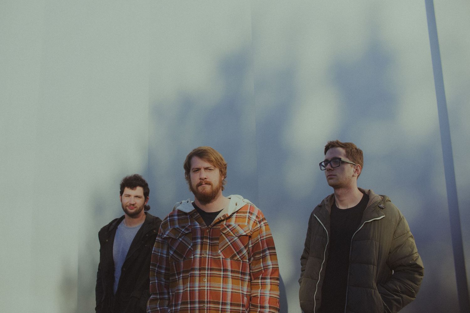 Group photo of band members in casual attire against a muted background.
