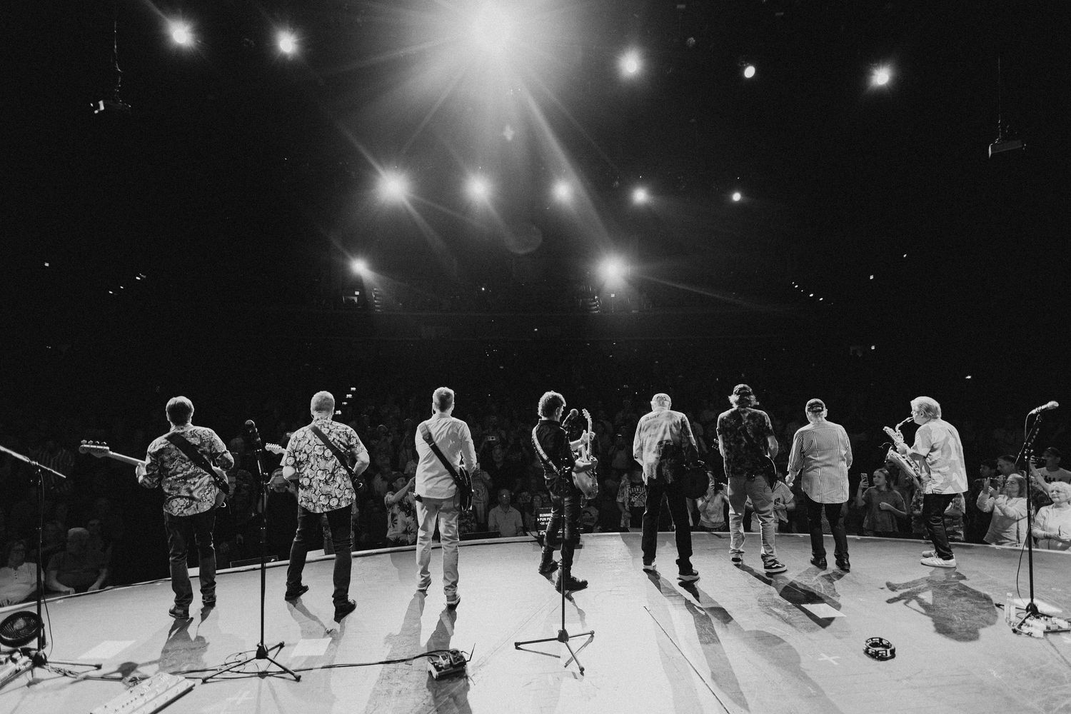 Wide concert hall view showing performers and crew during soundcheck or rehearsal.