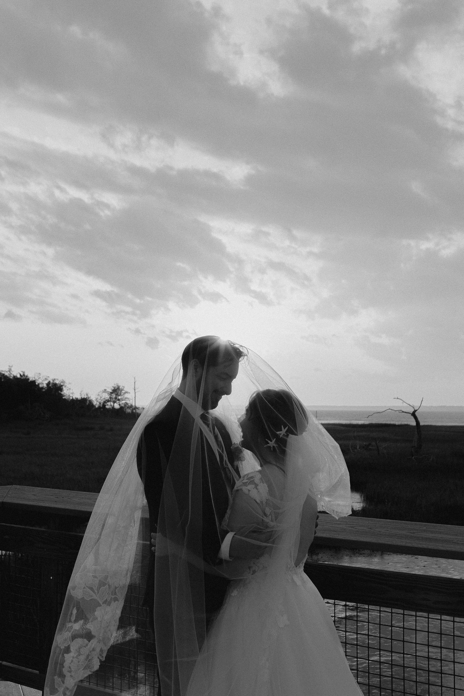 Silhouette of couple embracing at sunset against cloudy sky.