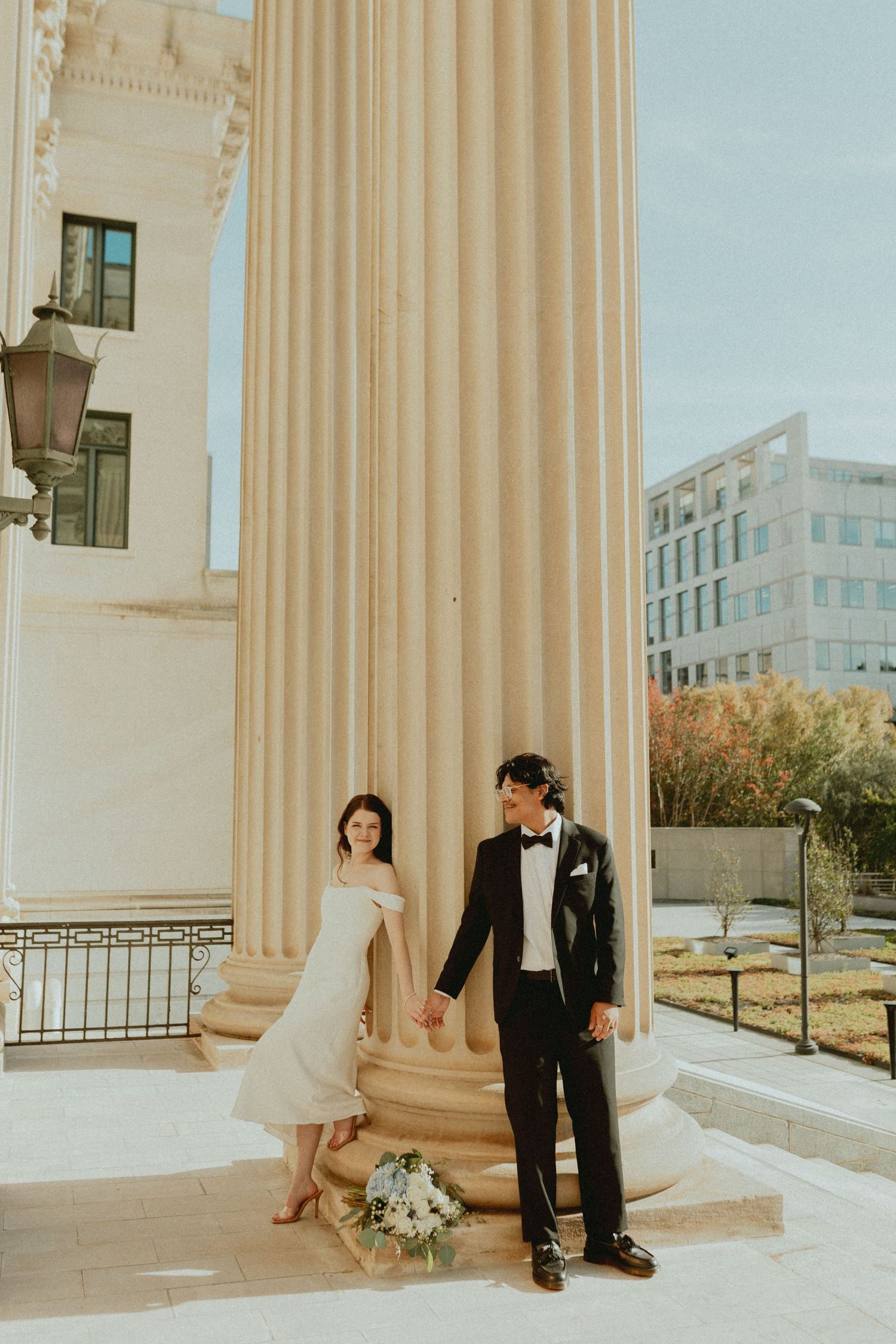 Elegant wedding photos taken between classical columns with warm sunlight.