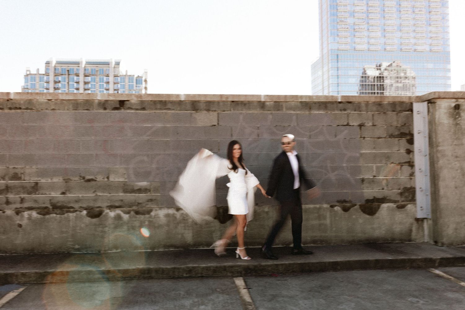 Urban engagement photoshoot along a concrete wall with dramatic lighting and shadows.