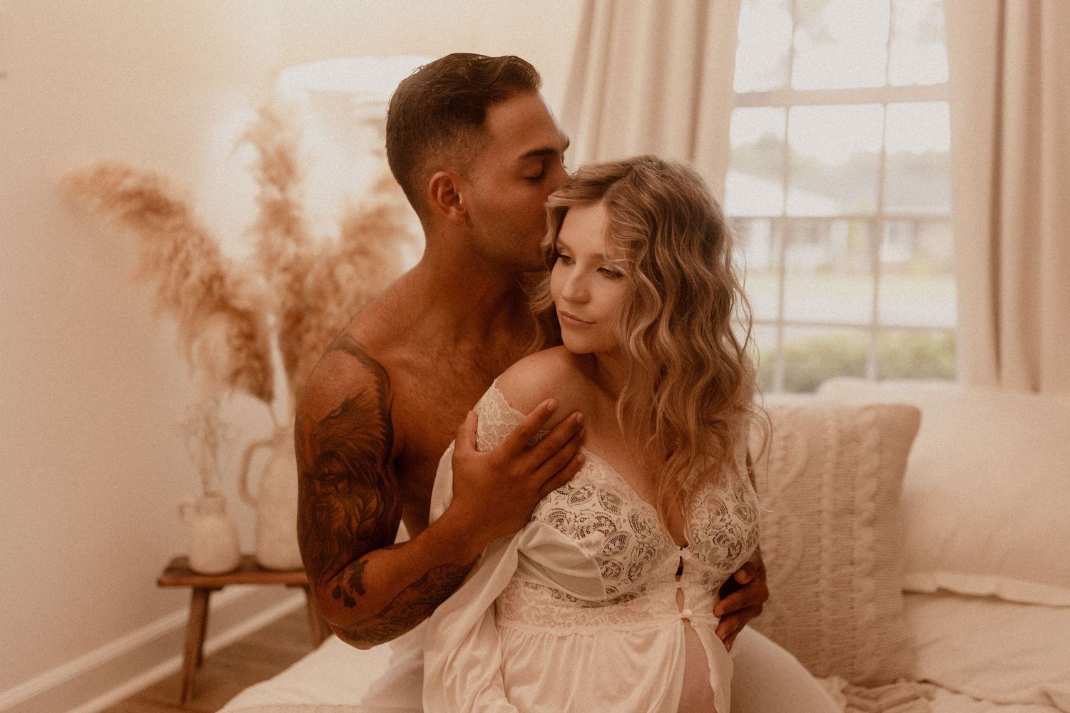 Intimate couples boudoir session in warm sepia tones with natural window lighting.