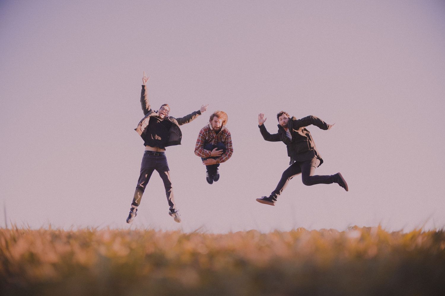 Silhouetted figures jump and leap across a series of connected sunset photos creating a dynamic panoramic sequence.