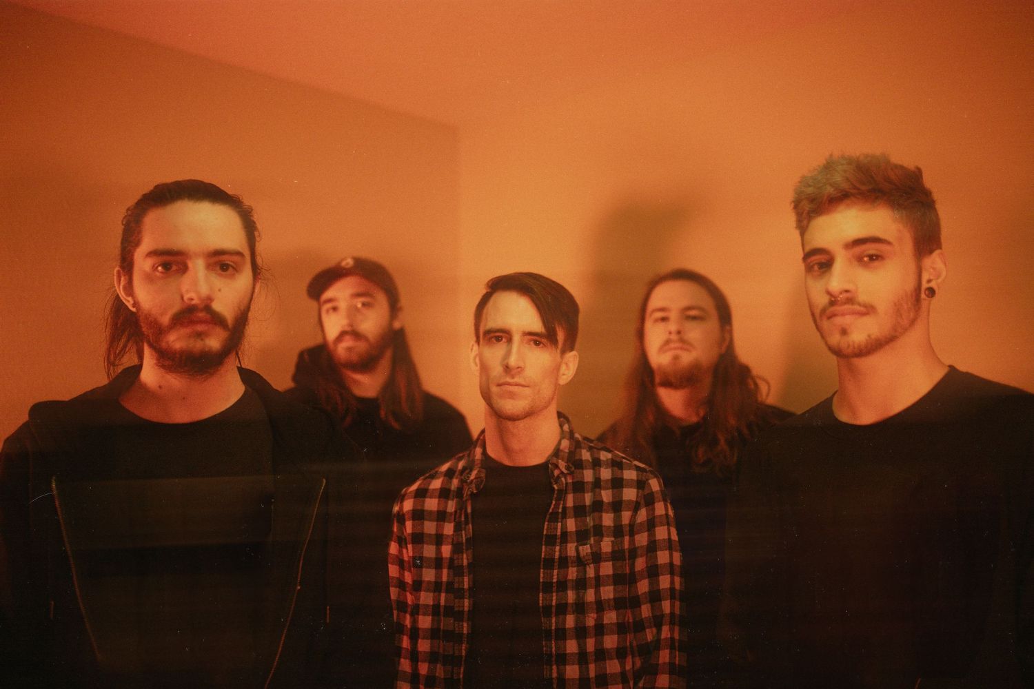 A series of four similar photos showing a group of people posing together in a dimly lit room with orange lighting.