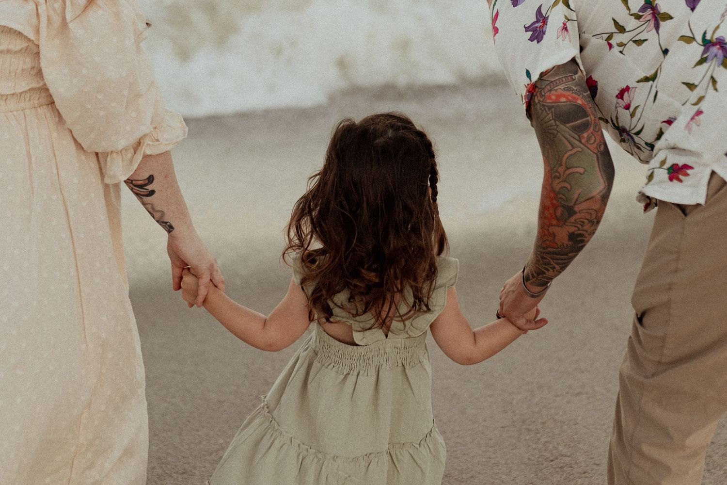 Family shares playful moment together on sandy beach.