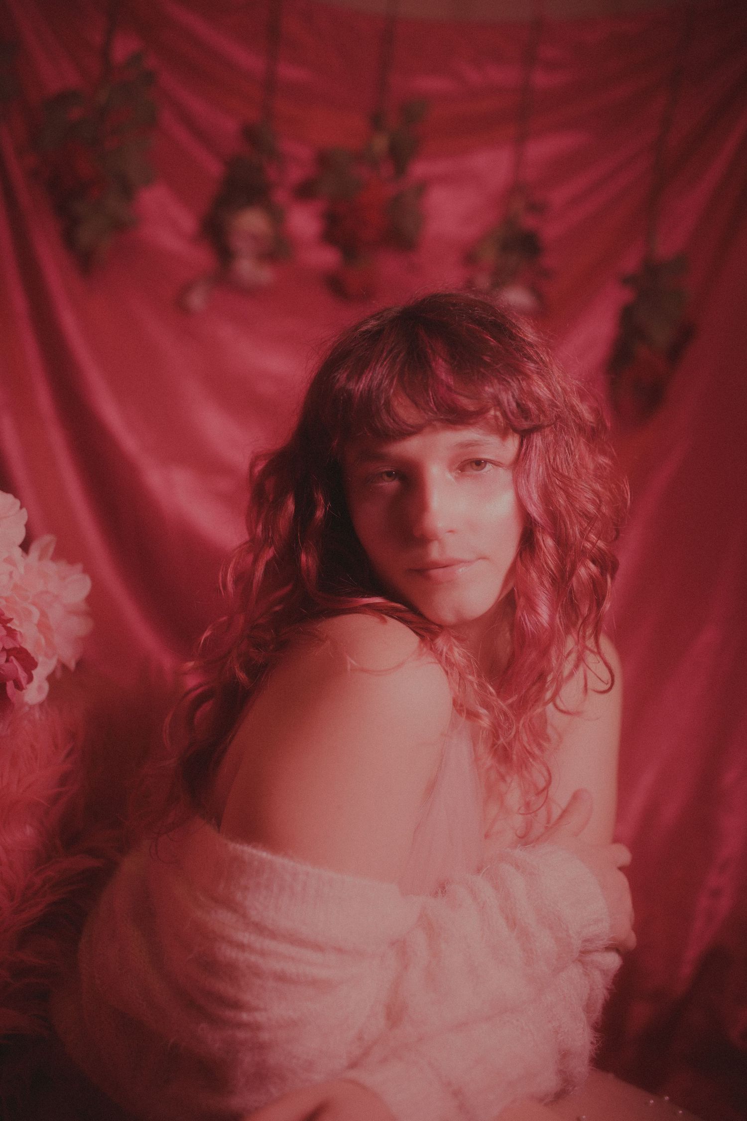 Dreamy portrait bathed in red light with soft focus and romantic styling.