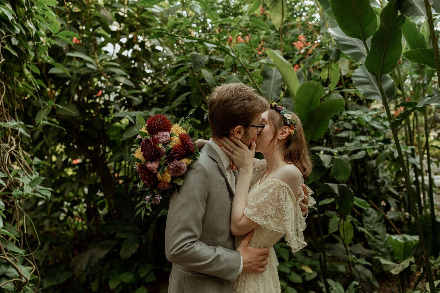 A couple shares an intimate moment surrounded by lush garden greenery.