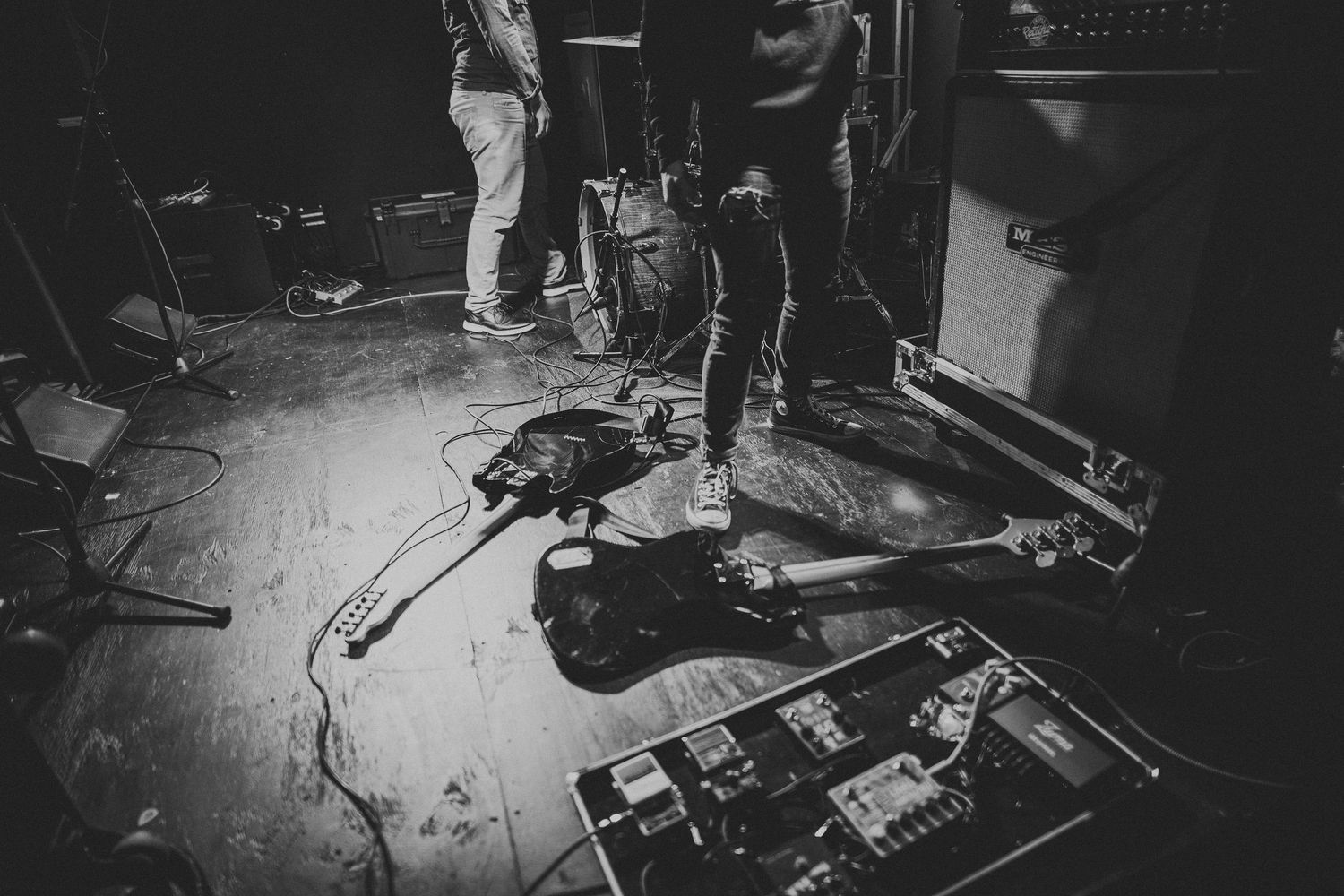 Musical equipment and guitar pedals scattered on stage floor during performance.