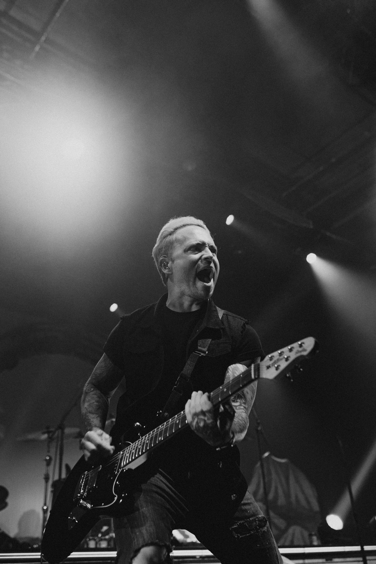 Energetic guitarist performing with electric guitar under bright stage lights.