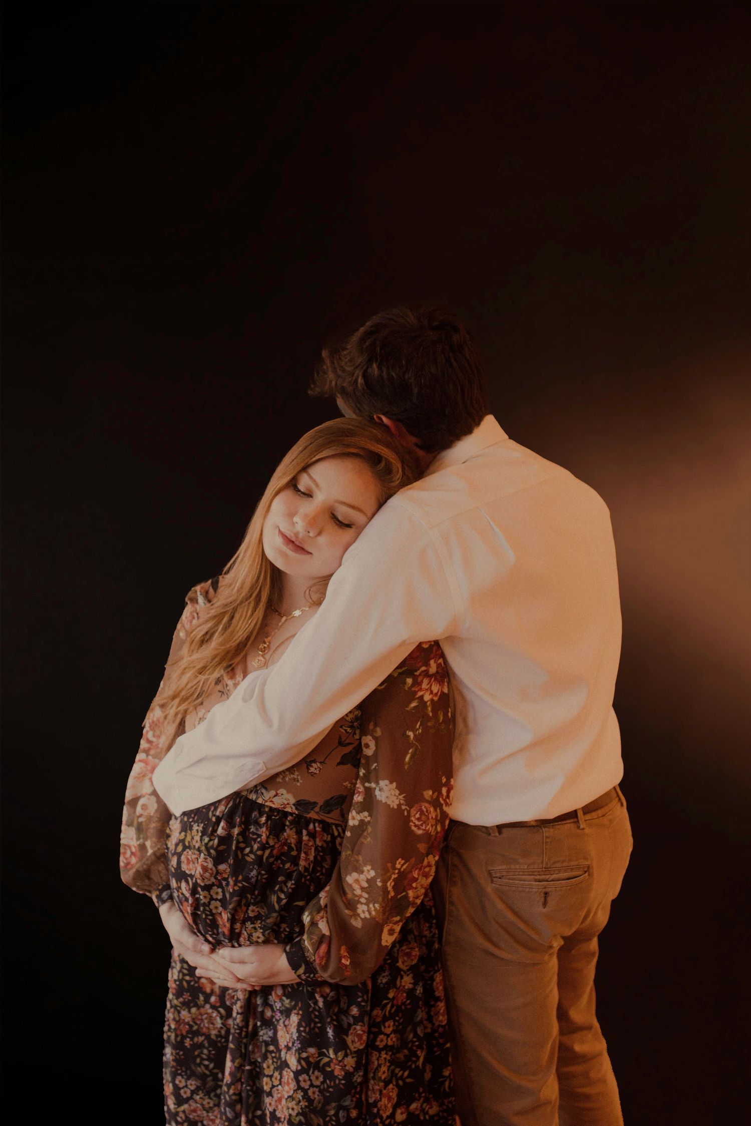 Couple embraces in intimate indoor portrait session.