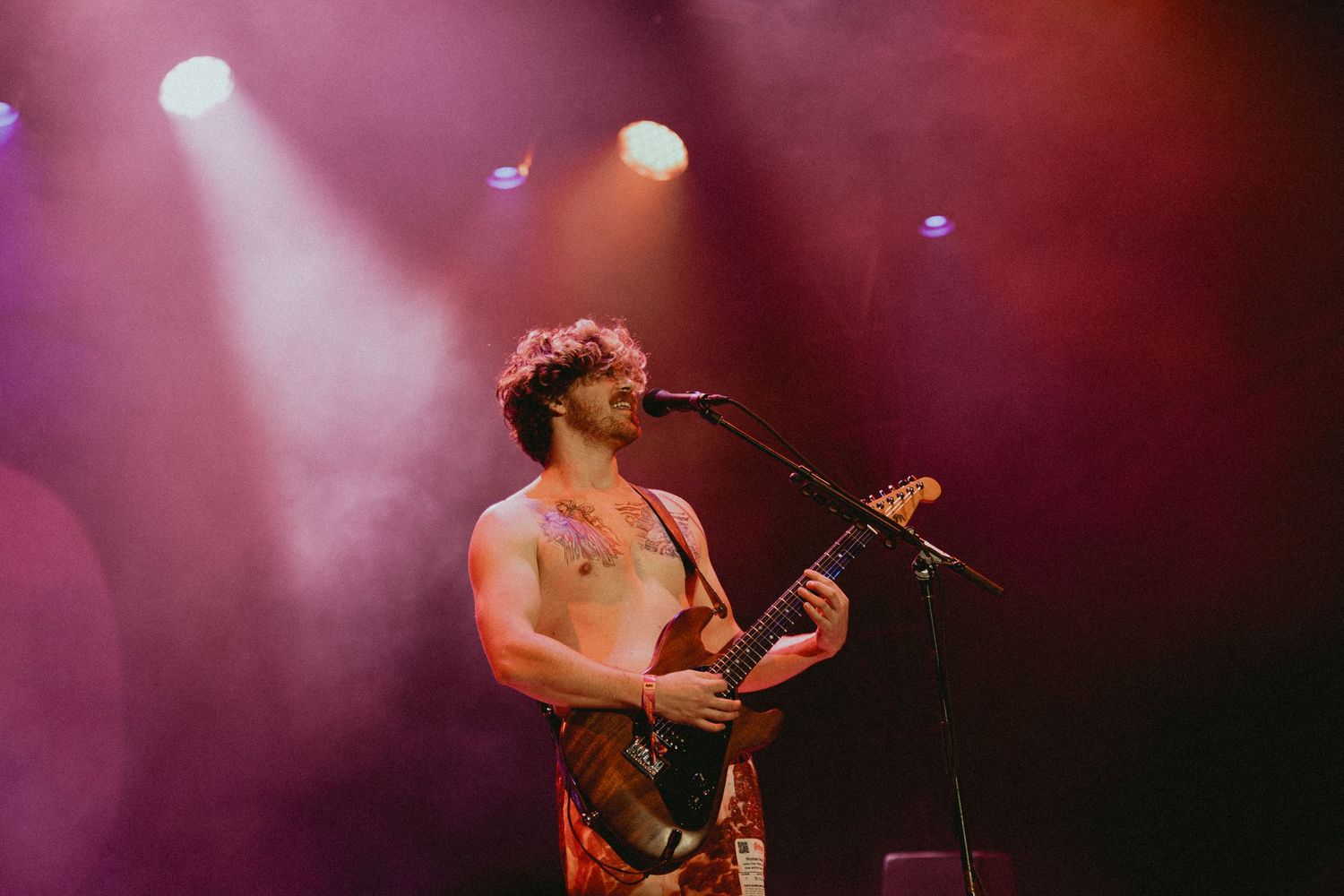 Concert performance with dramatic pink and purple stage lighting creating an atmospheric mood.