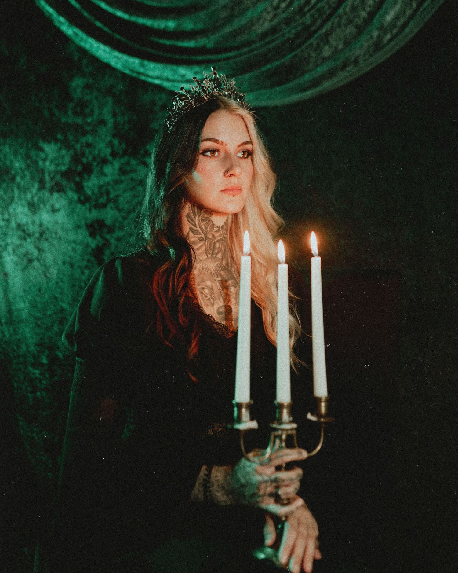 Moody portrait with lit candles against emerald green velvet backdrop.