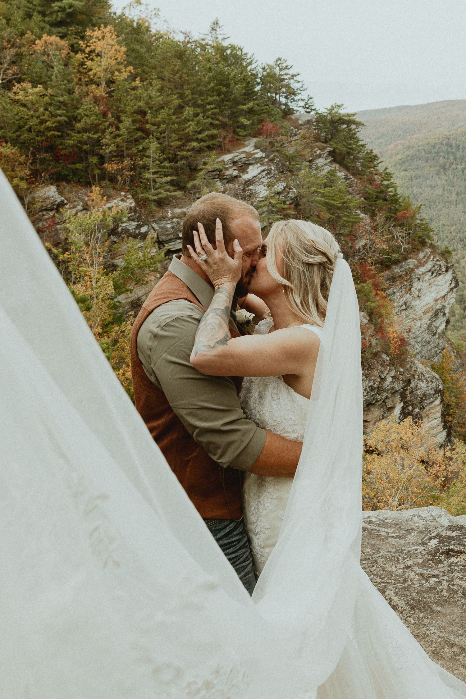 Wedding couple sharing intimate moments on a rocky mountain overlook with scenic views.