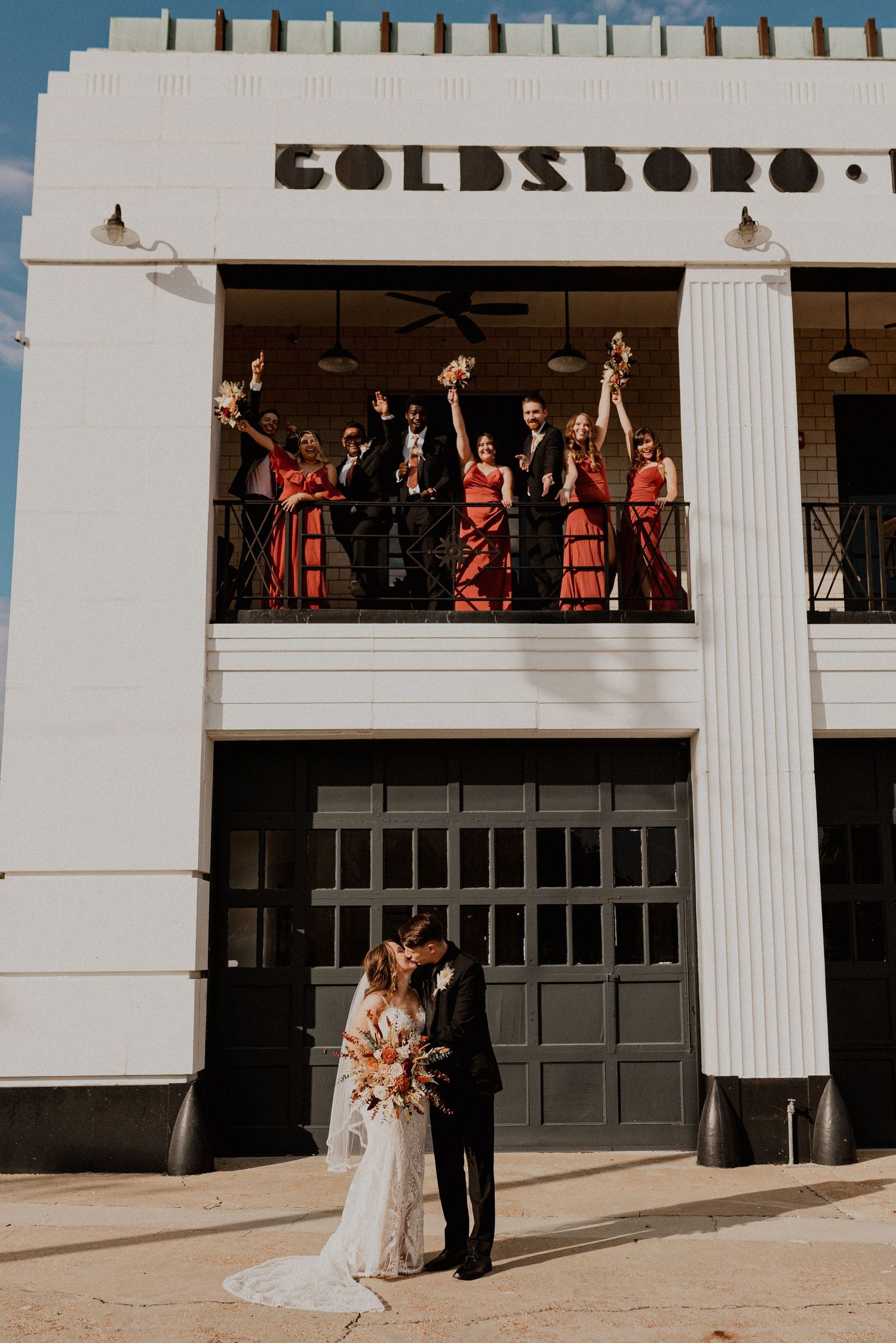 Modern architectural wedding venue with white columns and guests viewing from above.