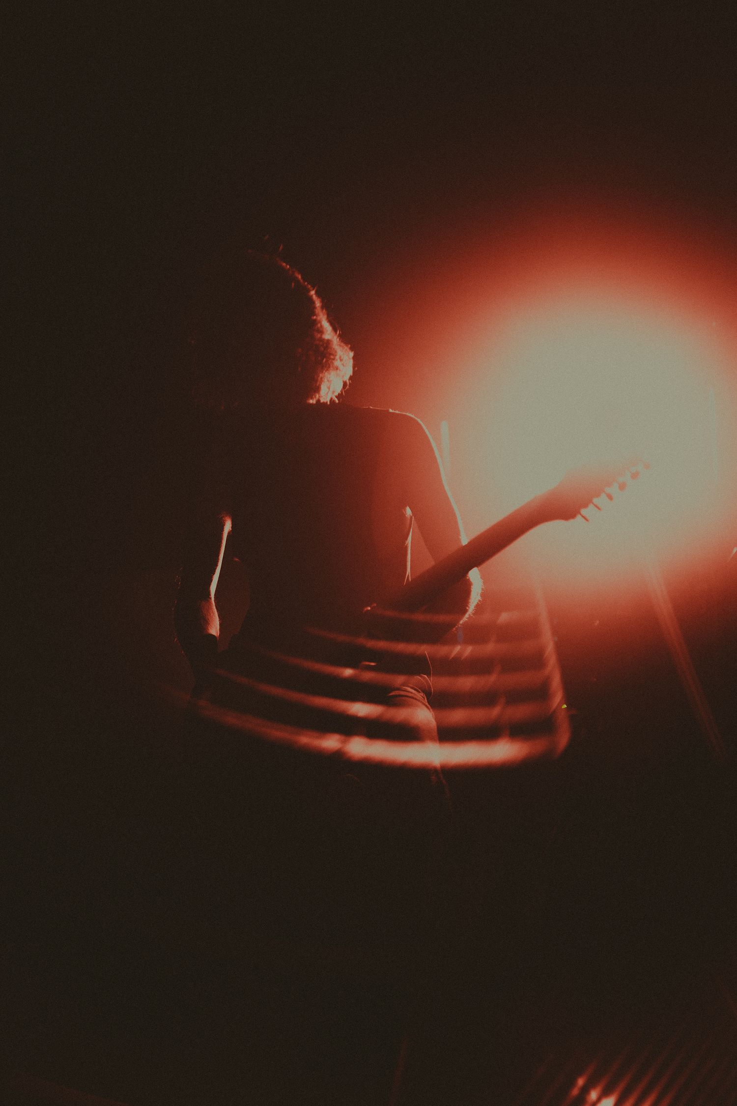 Silhouetted performer on stage with dramatic red lighting effects.