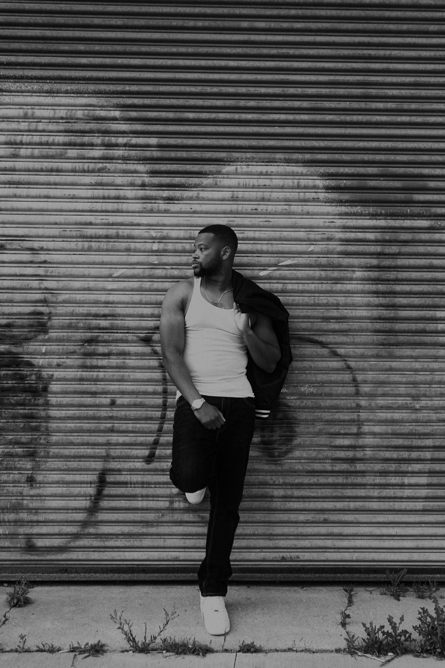 A person in casual attire poses against an industrial metal garage door background.