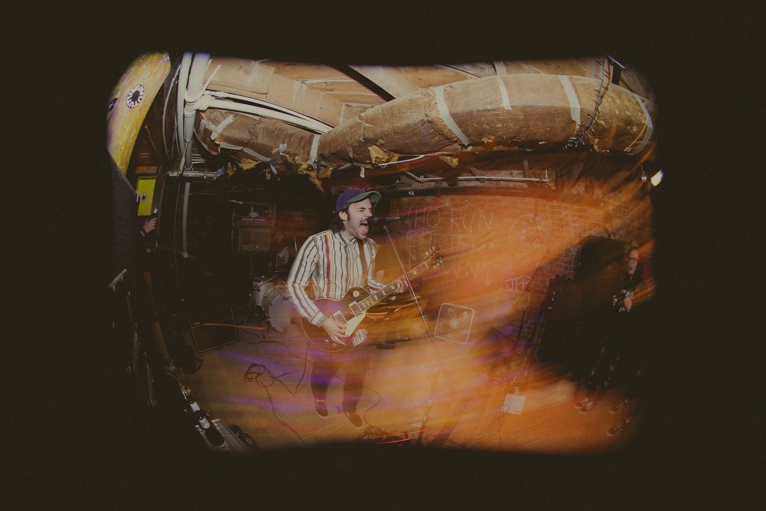 Musician performs on stage captured through distorted vintage camera effect.