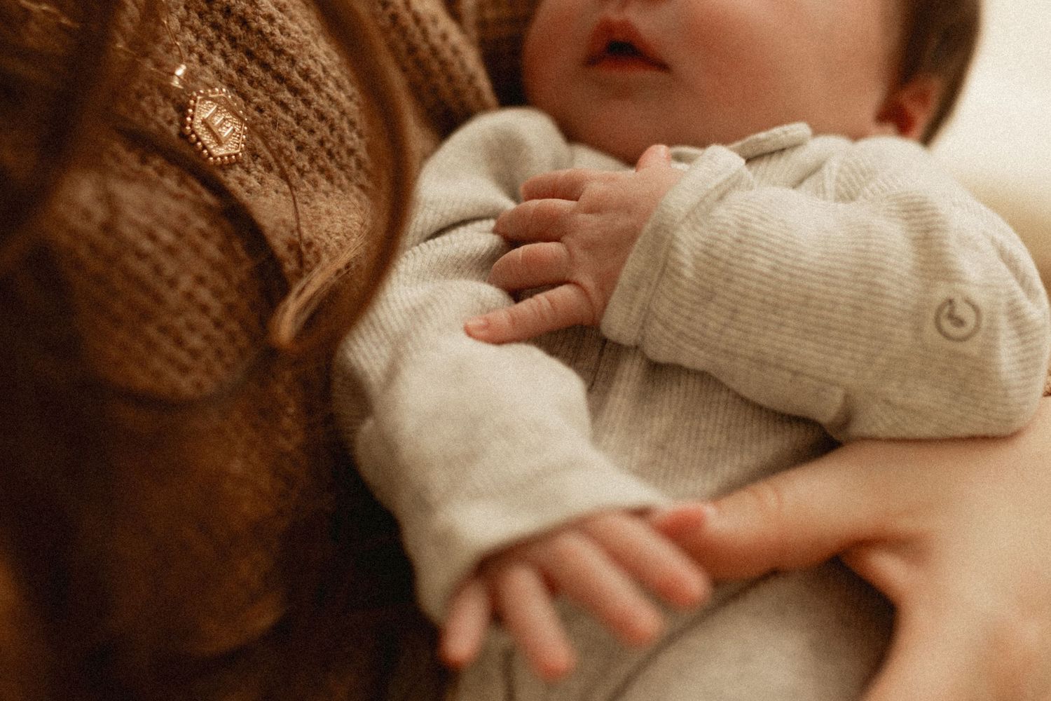 Tender moment of a newborn baby in soft knit clothing held close.