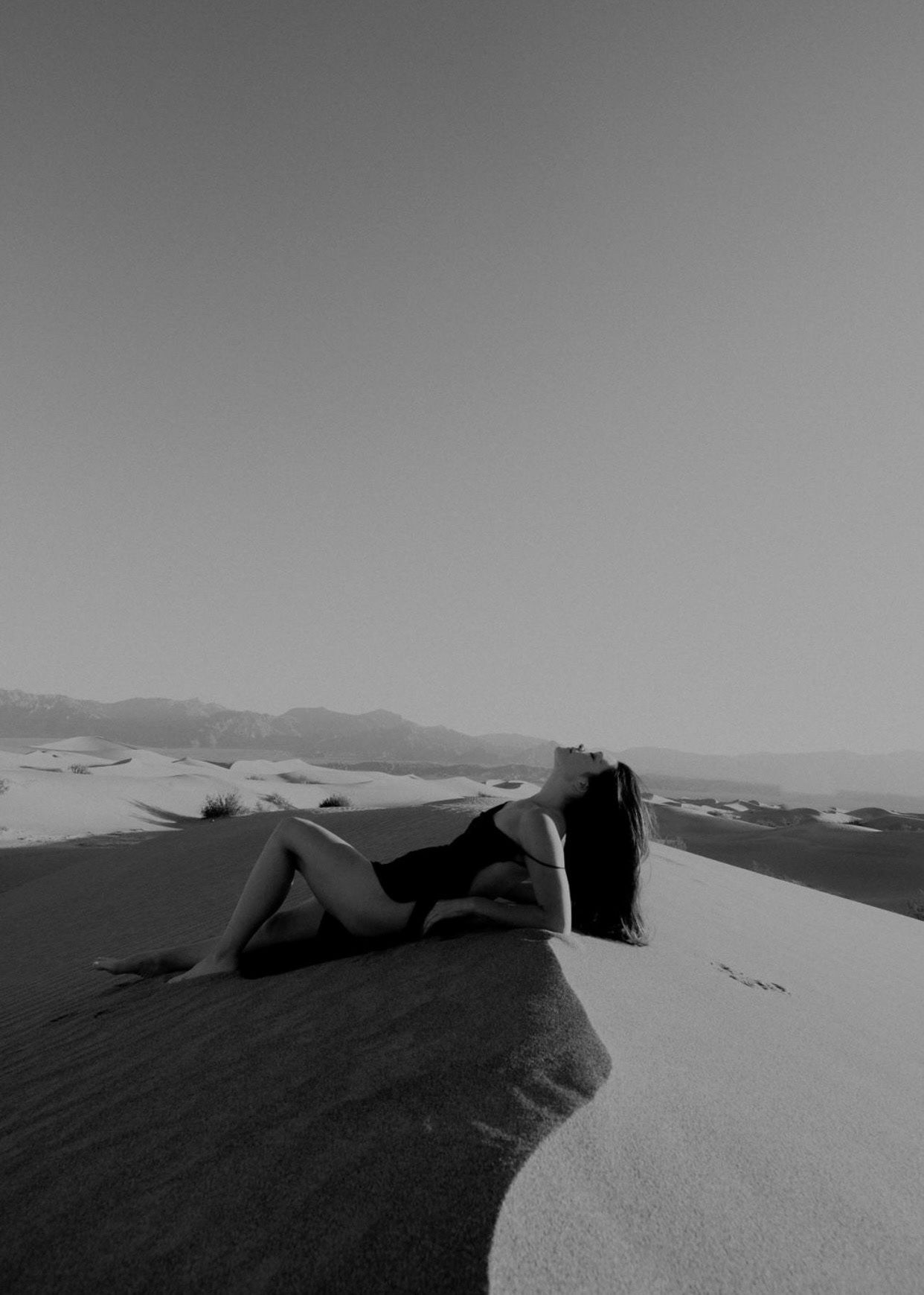 Minimalist black and white landscape photography of sand dunes with strong shadow contrast.
