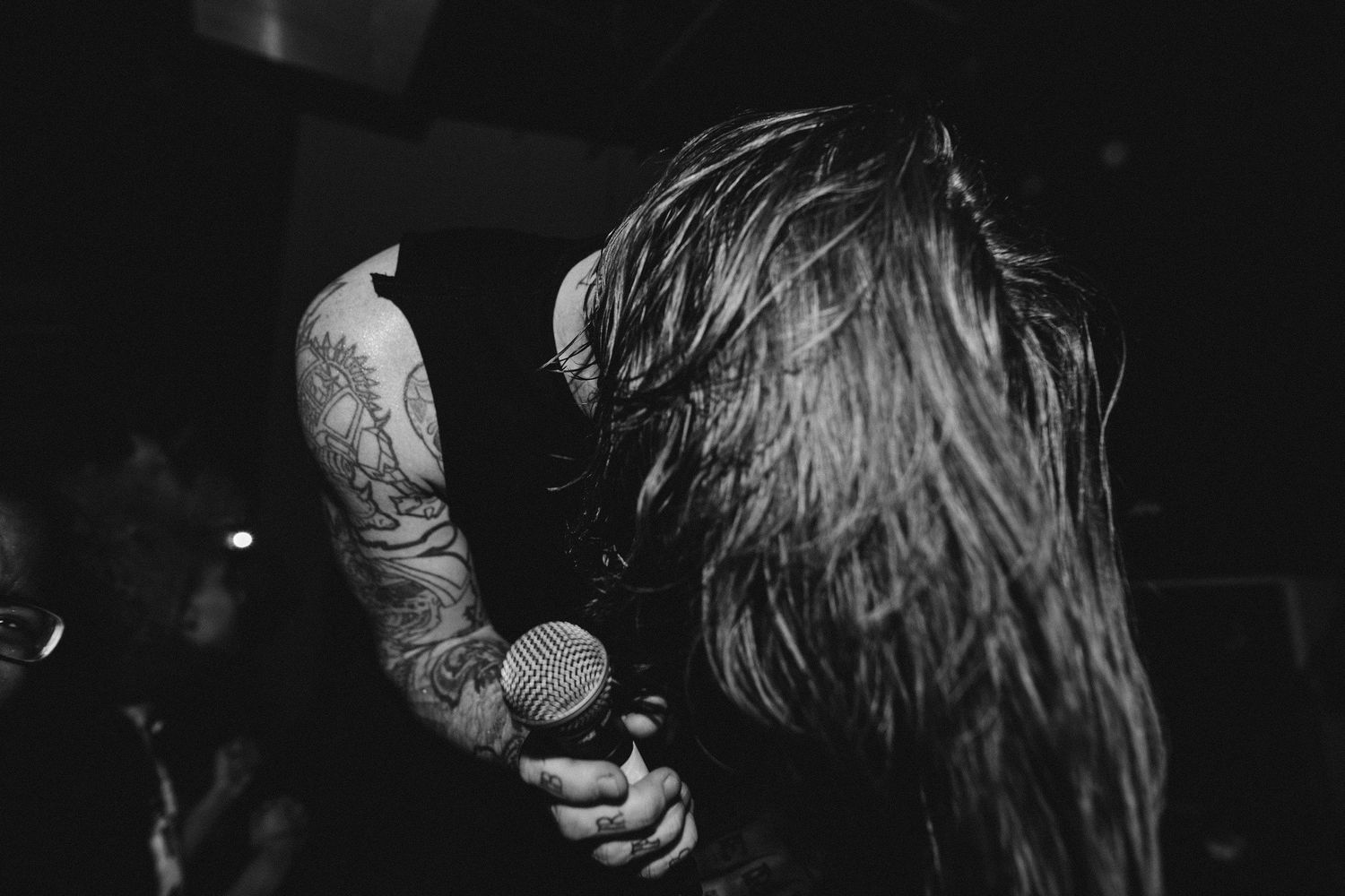 Dramatic black and white photo of musicians performing on a dimly lit stage.