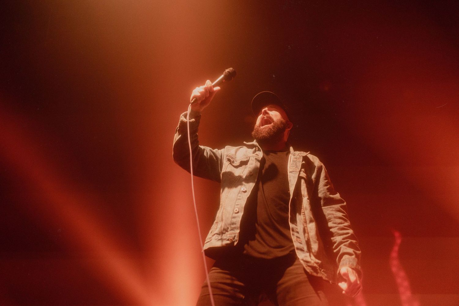 Dynamic concert performance captured in warm red lighting with performers energetically moving on stage.
