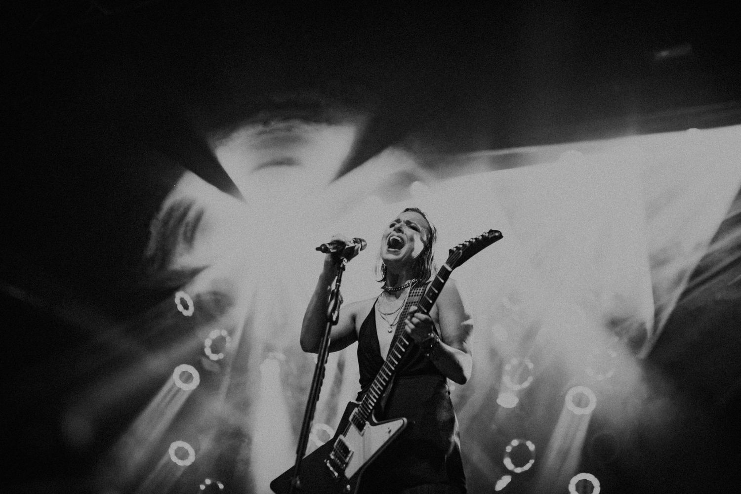 Silhouetted guitarist performing on stage with bright spotlights creating dramatic atmosphere.