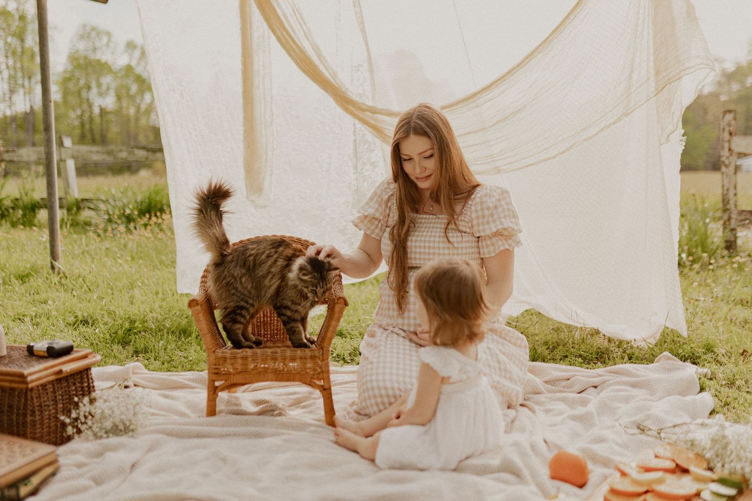 A picnic scene with white linens and blankets set up outdoors on a sunny day.