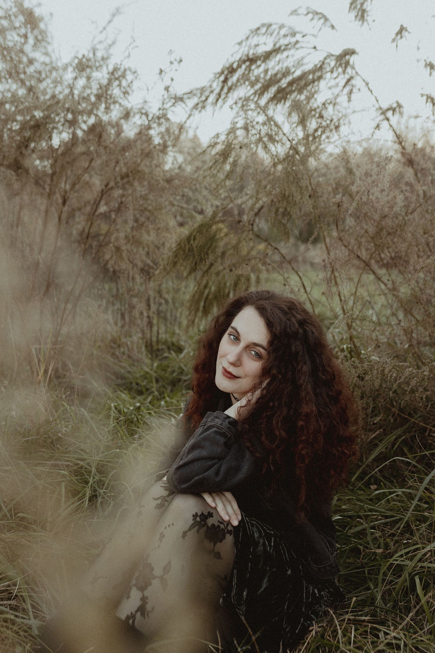 Artistic portrait in tall grass with moody autumn lighting and natural textures.
