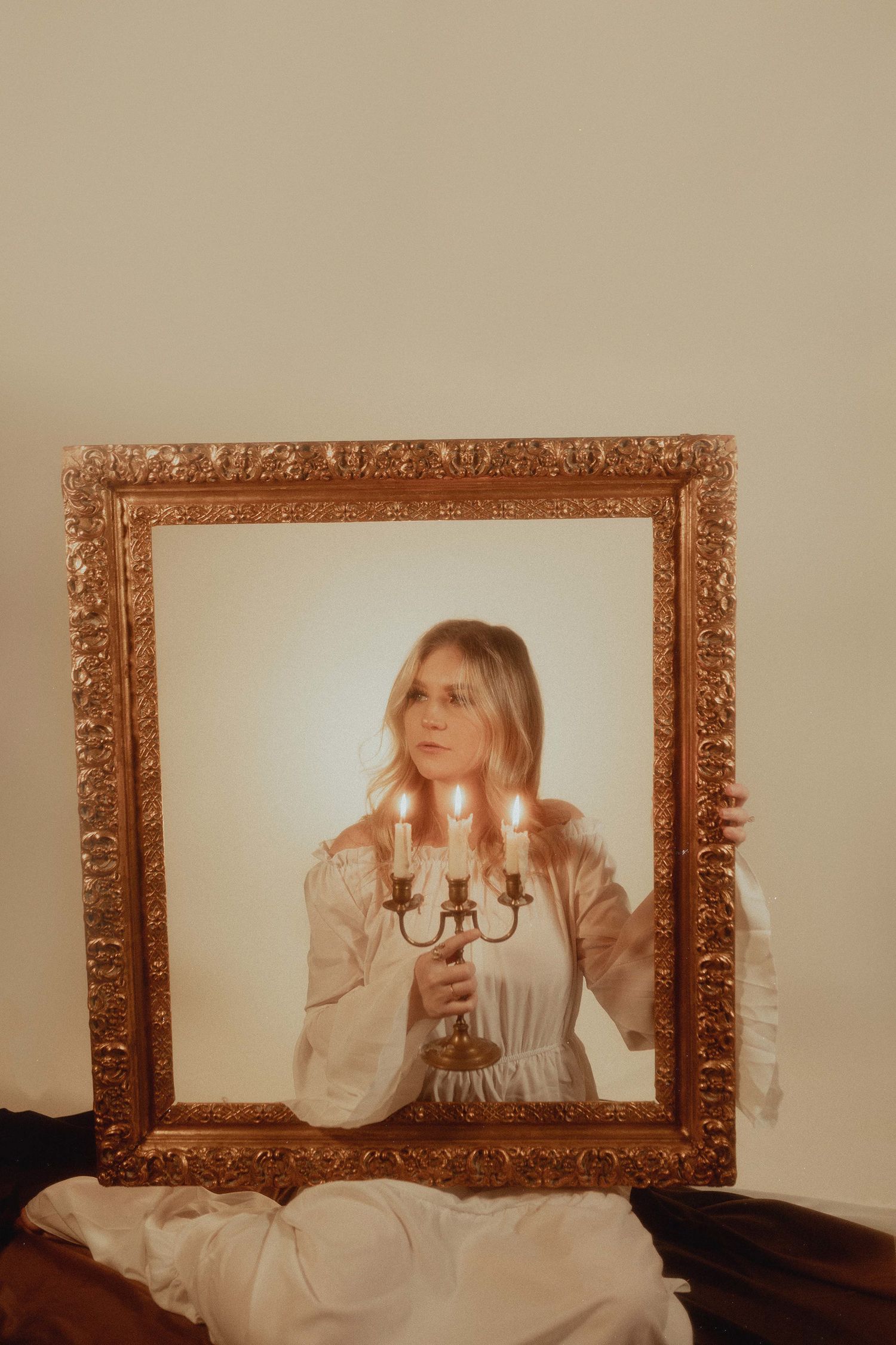 Vintage-style photo in an ornate gold frame featuring candlesticks and soft lighting.