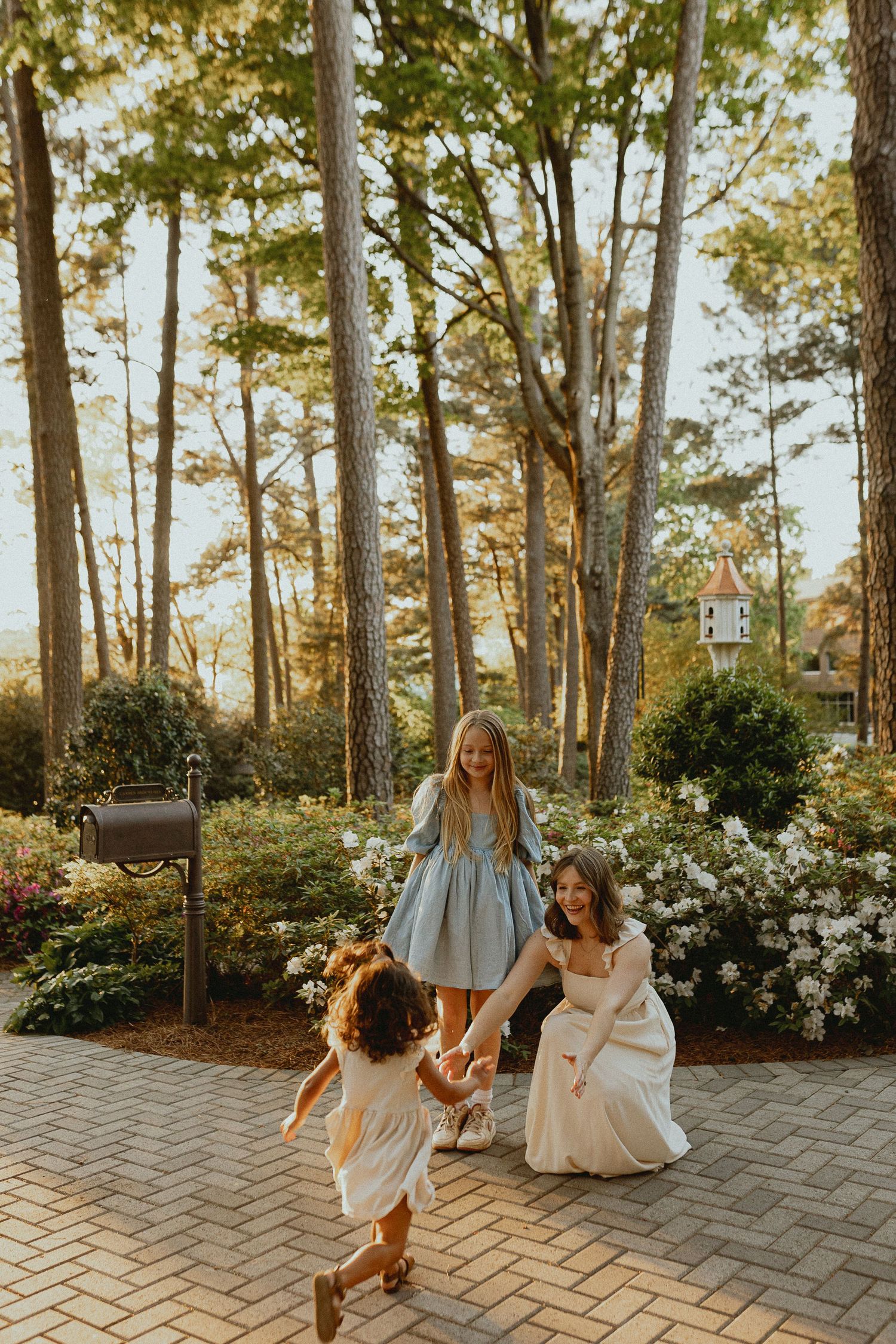 Playful dance movements captured on a brick patio with garden and forest backdrop.
