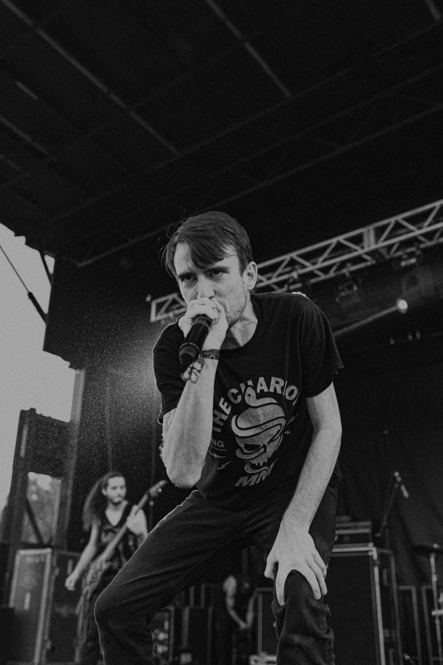 High-energy performance captured in black and white on a concert stage with overhead lighting.