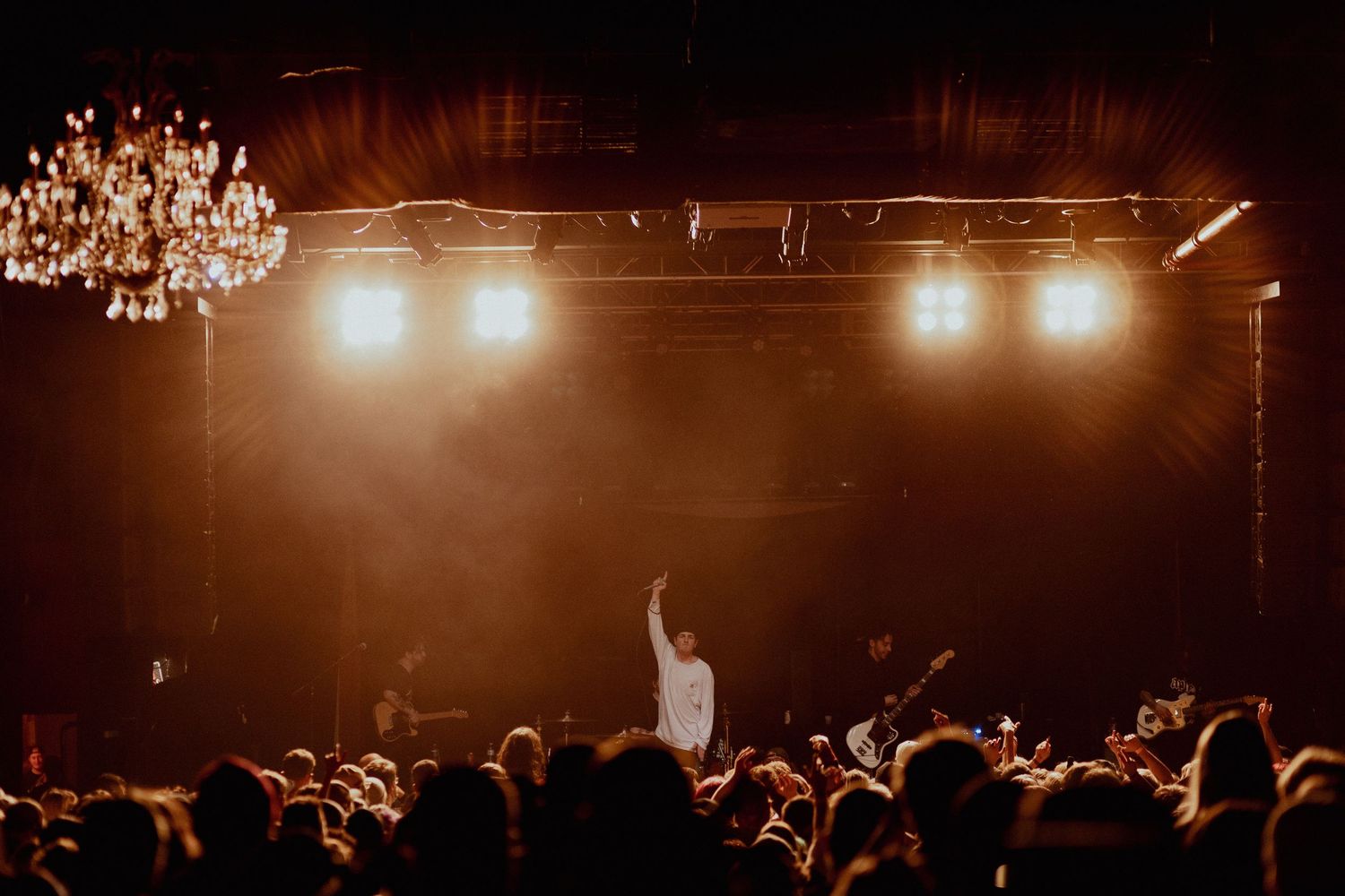 Concert crowd silhouettes against warm stage lighting creating an atmospheric live music scene.