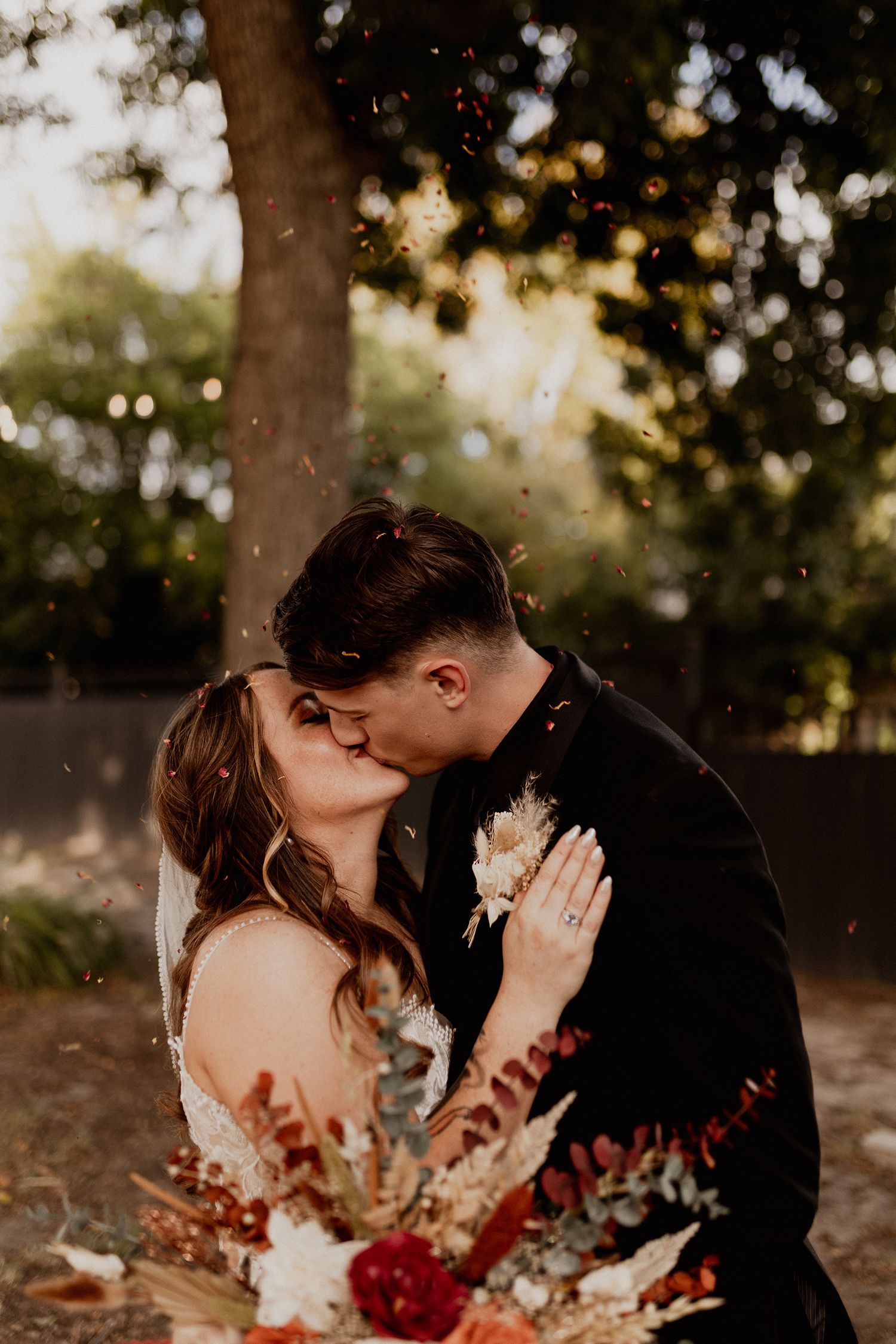 A romantic autumn wedding photo with falling leaves and warm lighting.