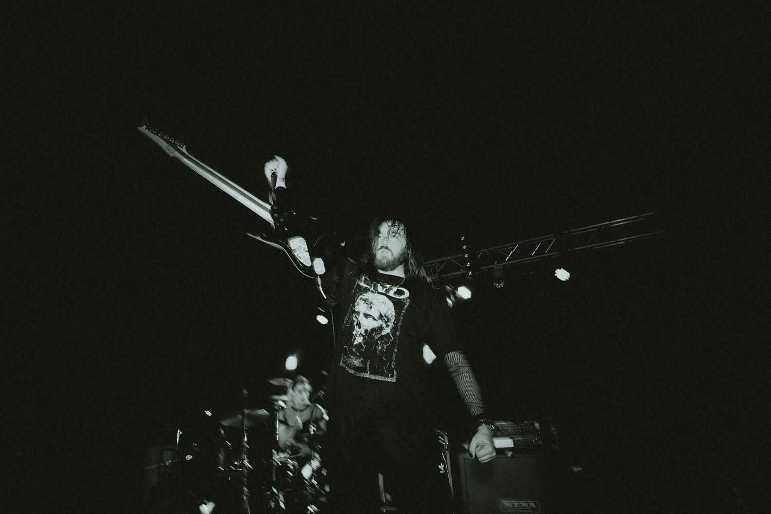 Musicians perform on darkened stage with dramatic spotlighting.