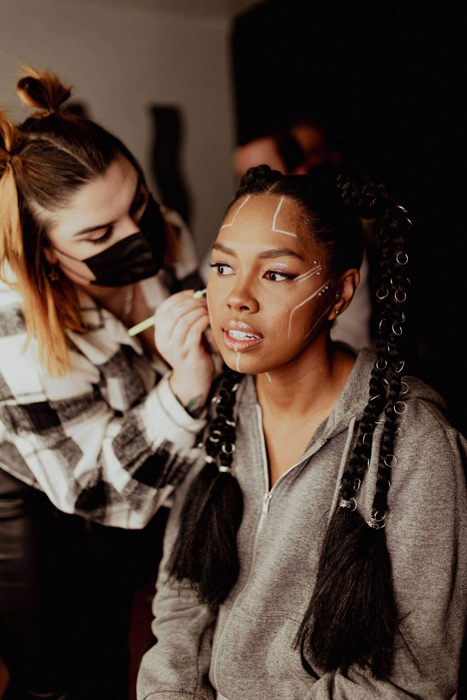 Makeup artist applies cosmetics to model in warmly lit indoor setting.