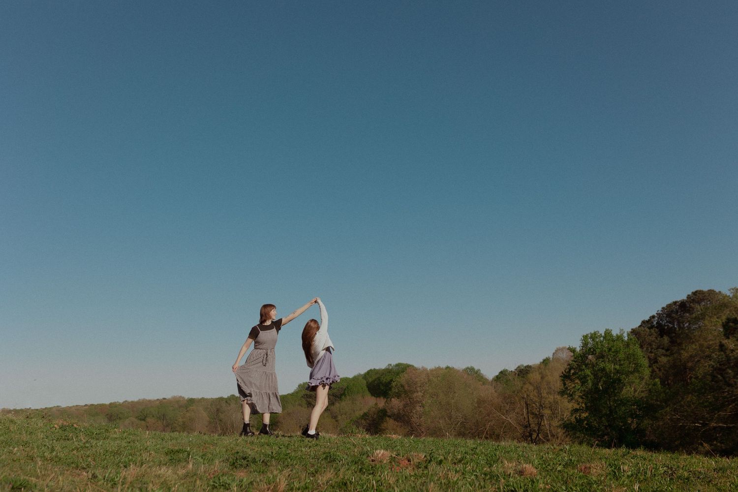 Distant silhouettes of people walking on a hilltop against blue sky.