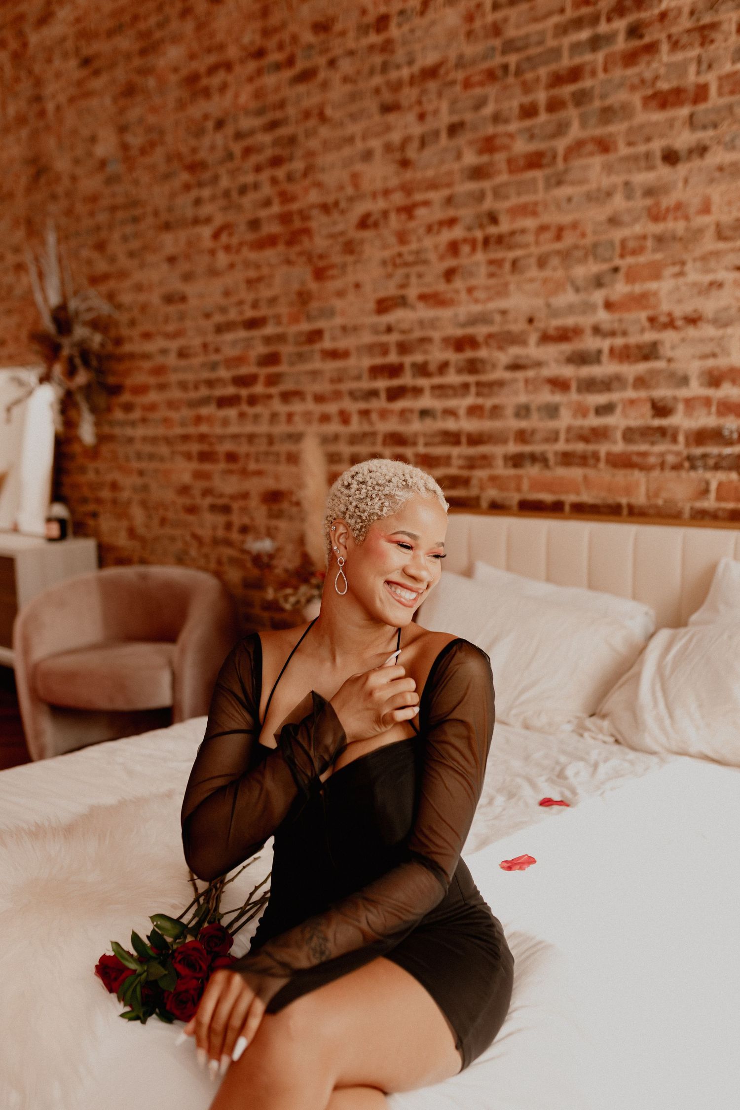 Intimate boudoir photoshoot with exposed brick wall background and black long sleeve top.