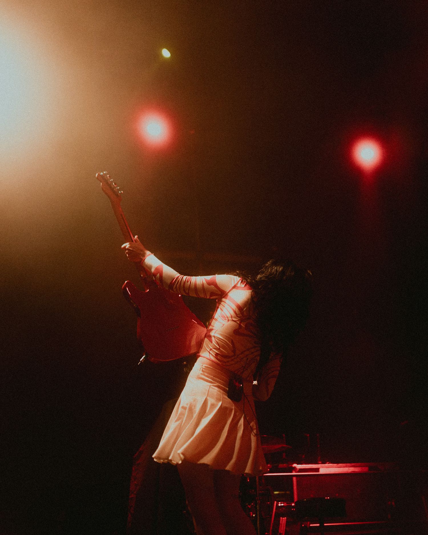 Concert performer silhouetted against red stage lights during an energetic live music performance.