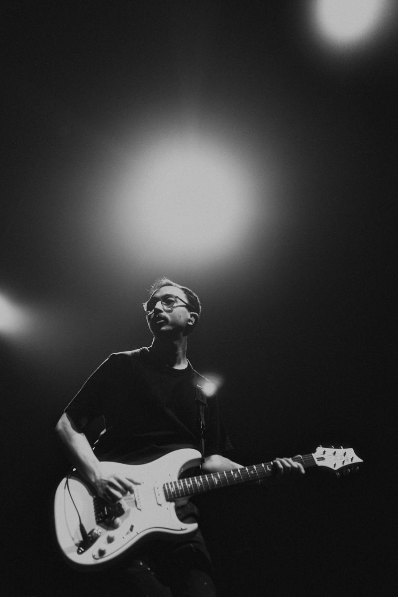 Musicians playing electric guitars in dramatic black and white stage lighting.