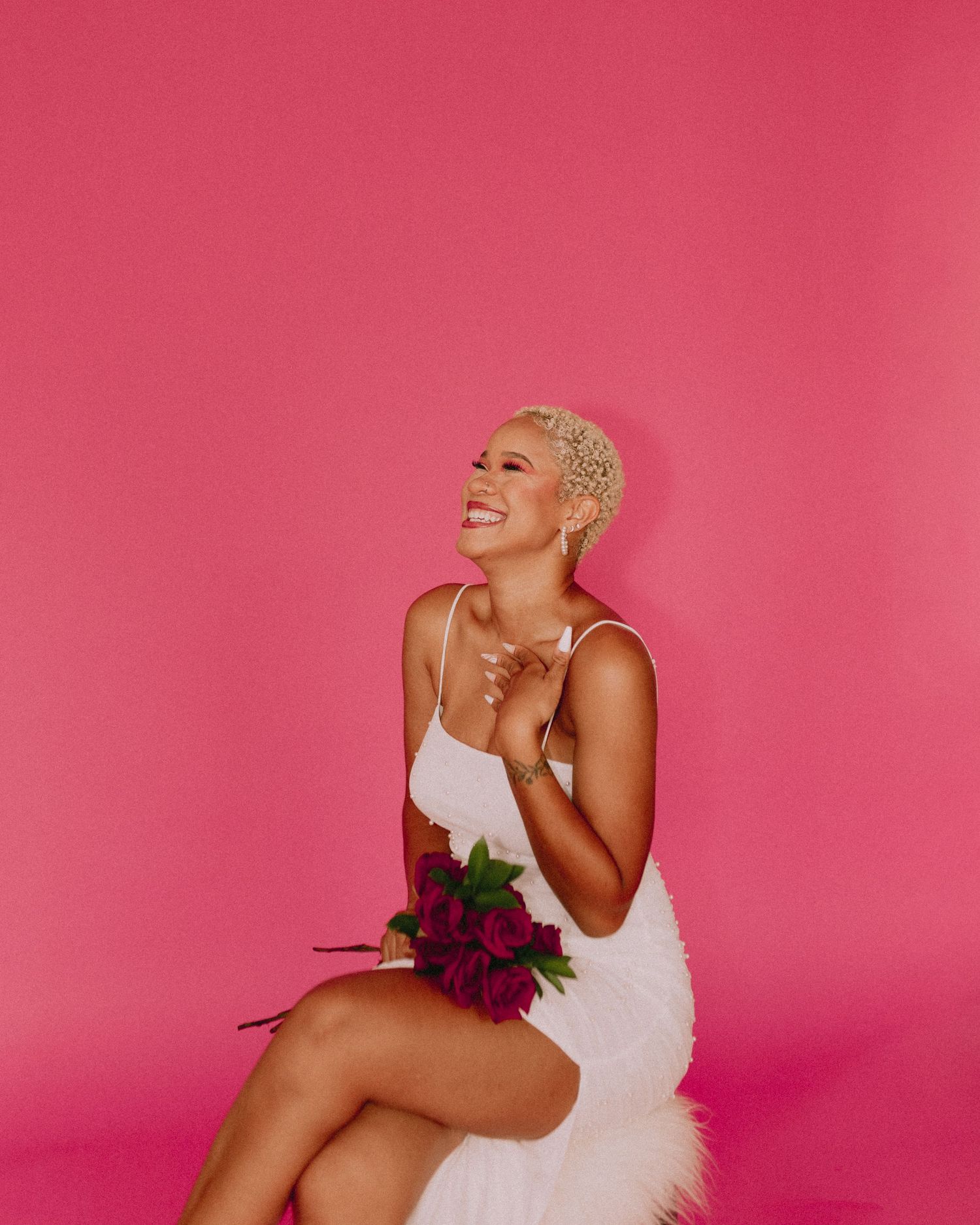 Glamour photography session featuring white tulle dress against vibrant pink background.