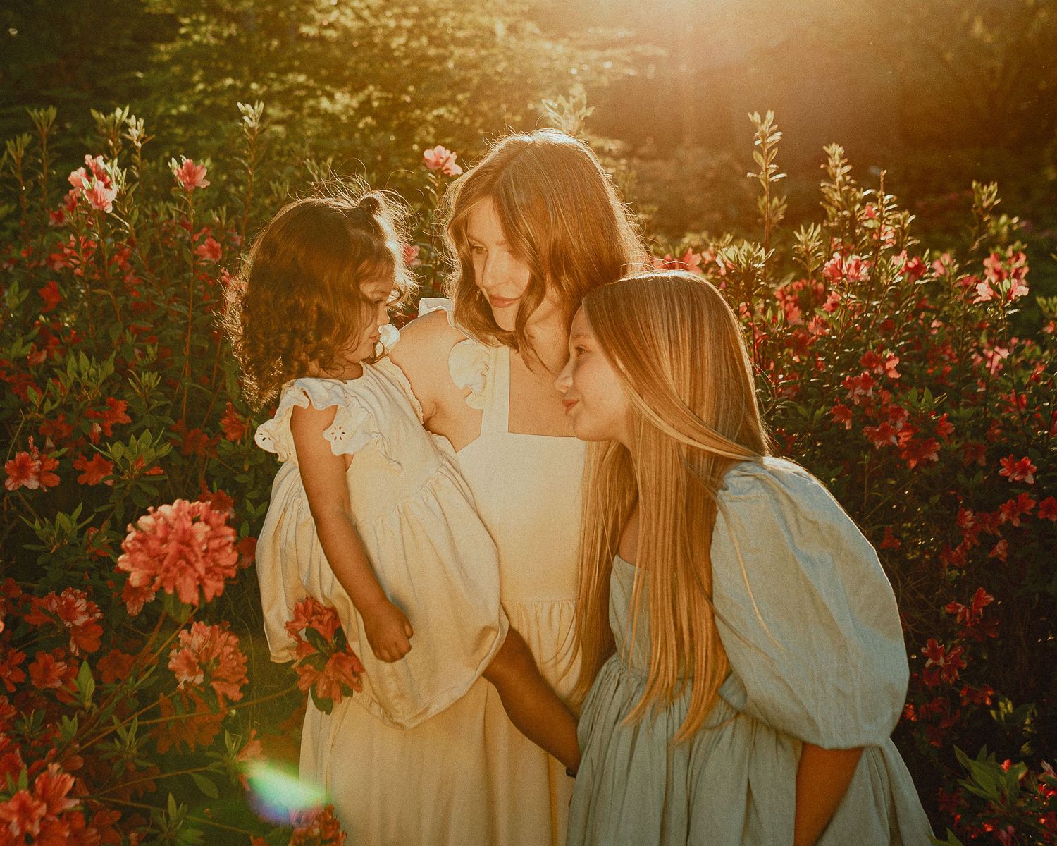 Golden sunset light illuminates a dreamy garden photoshoot with flowing dresses.