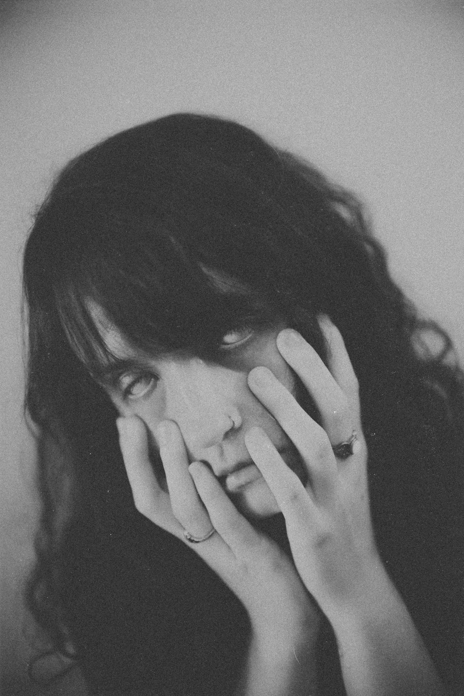 Black and white portrait series showing hands covering face with dramatic shadows.