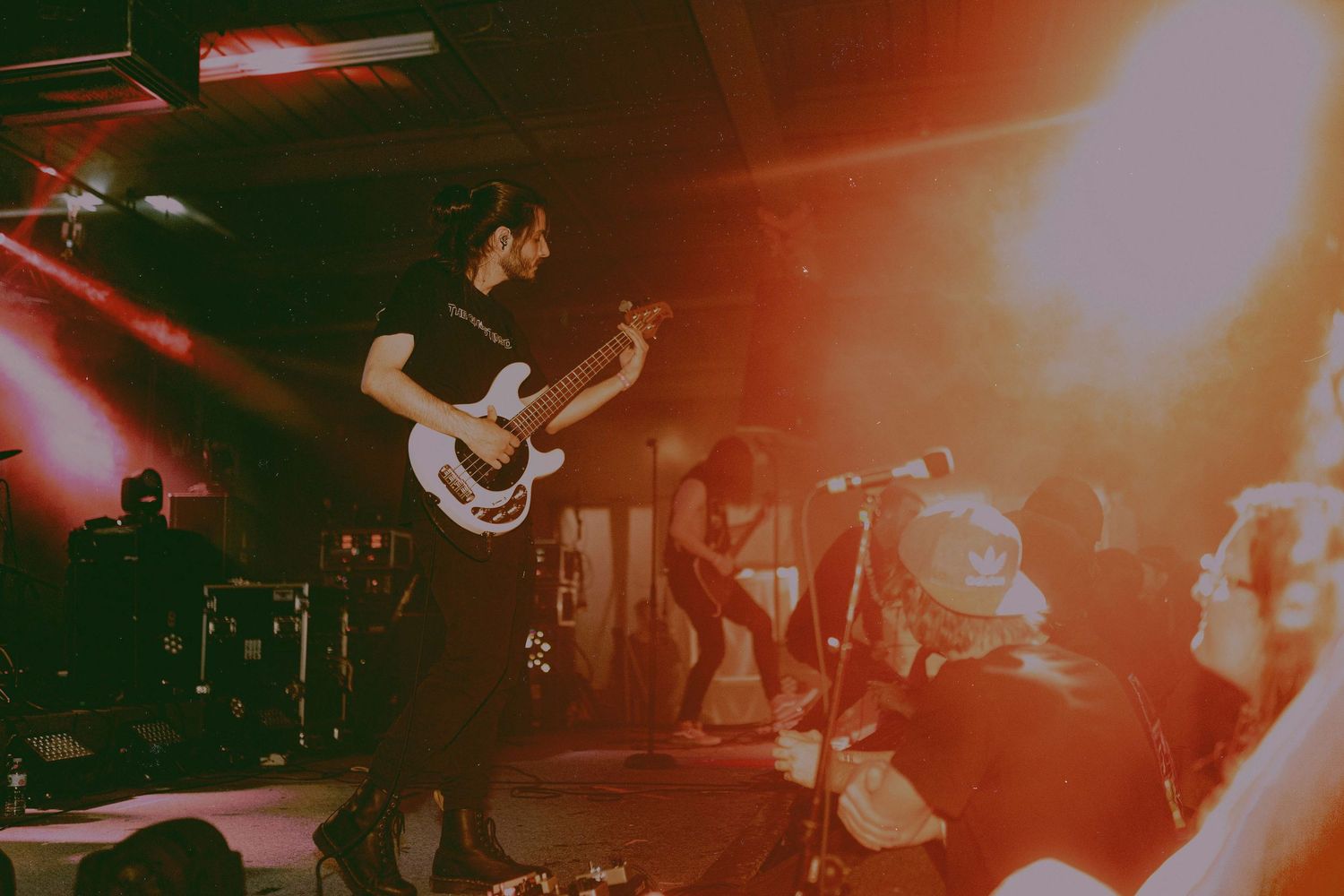 Concert stage bathed in warm red lighting with performers and equipment silhouettes.