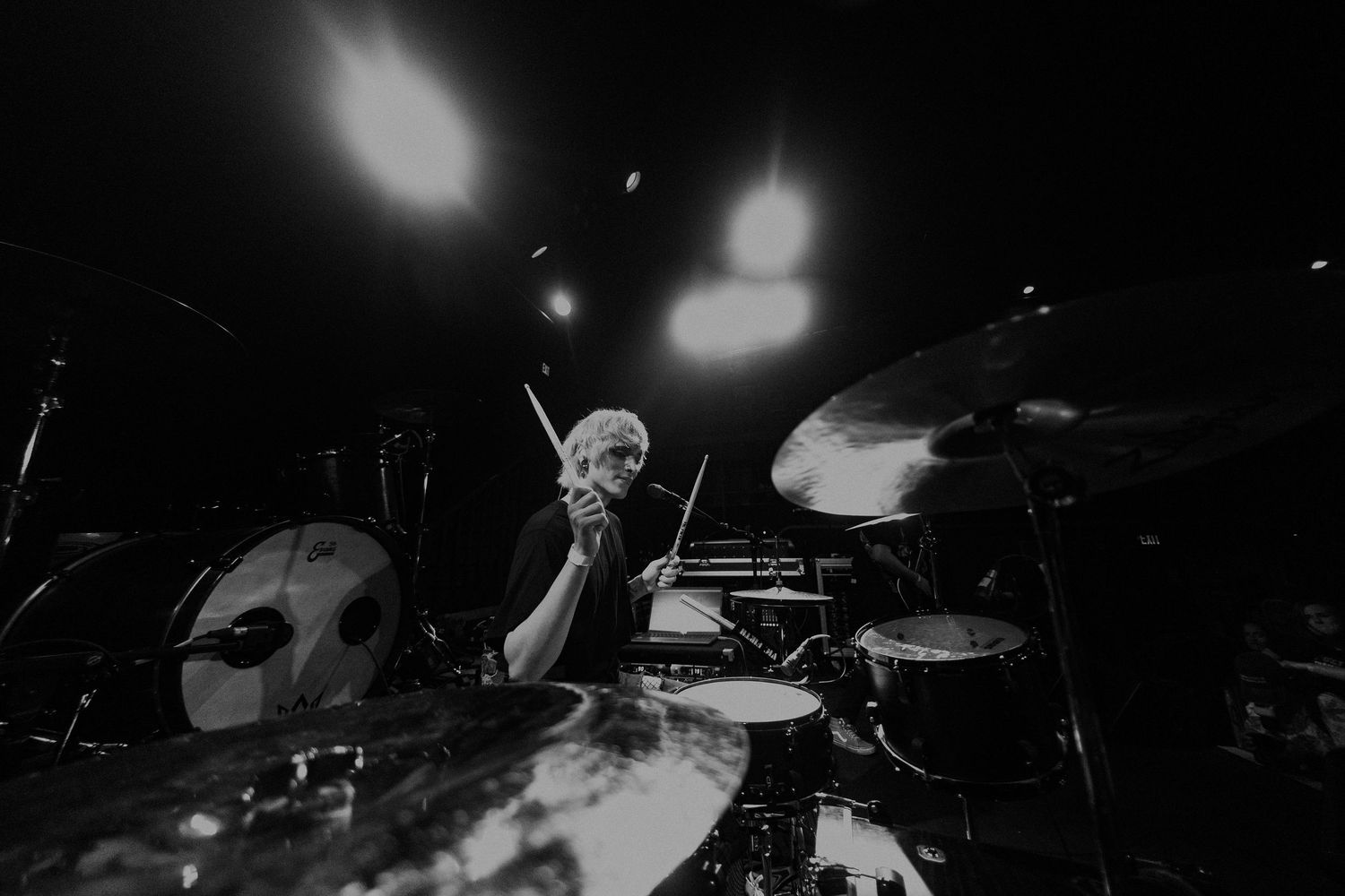 Black and white concert photo showing intense live music performance with dramatic stage lighting.