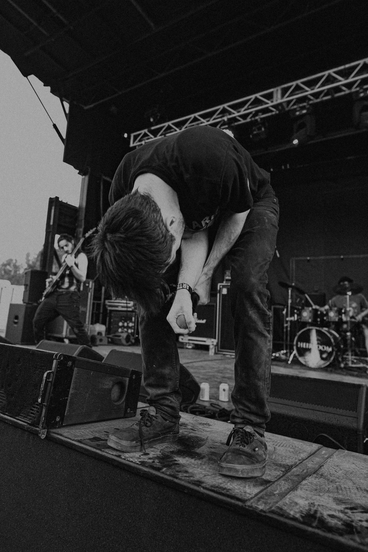 Performer bending over on stage during intense live music performance.
