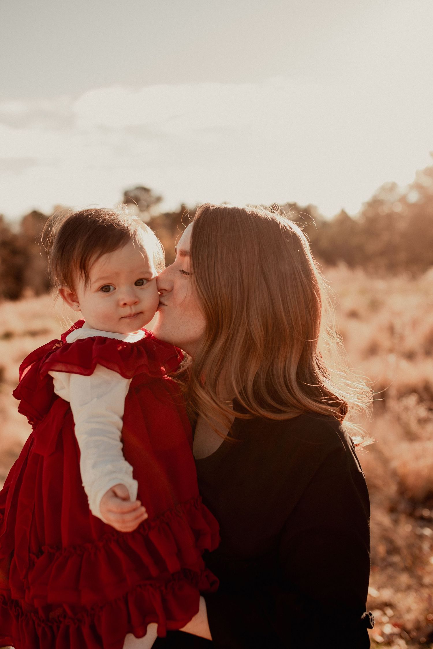 Sunset family portraits with red and black outfits in golden hour lighting.